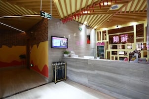A reception area with a counter, a television mounted on the wall, and a sign indicating the direction to the bathroom.