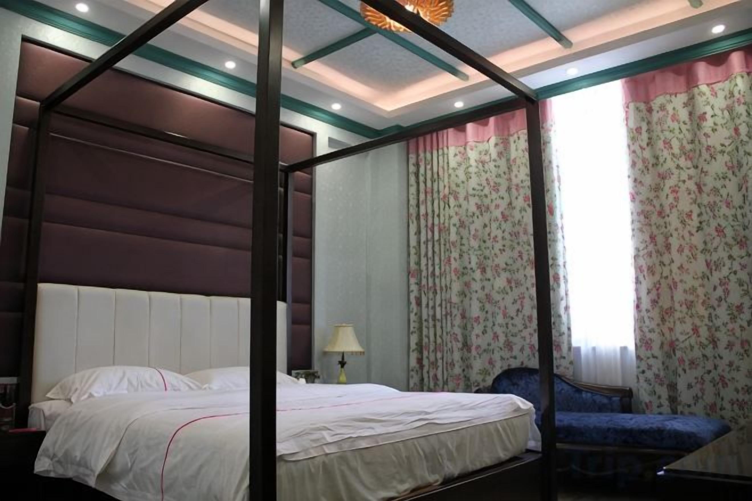A four-poster bed with a headboard, a bedside table with a lamp, and a chair.