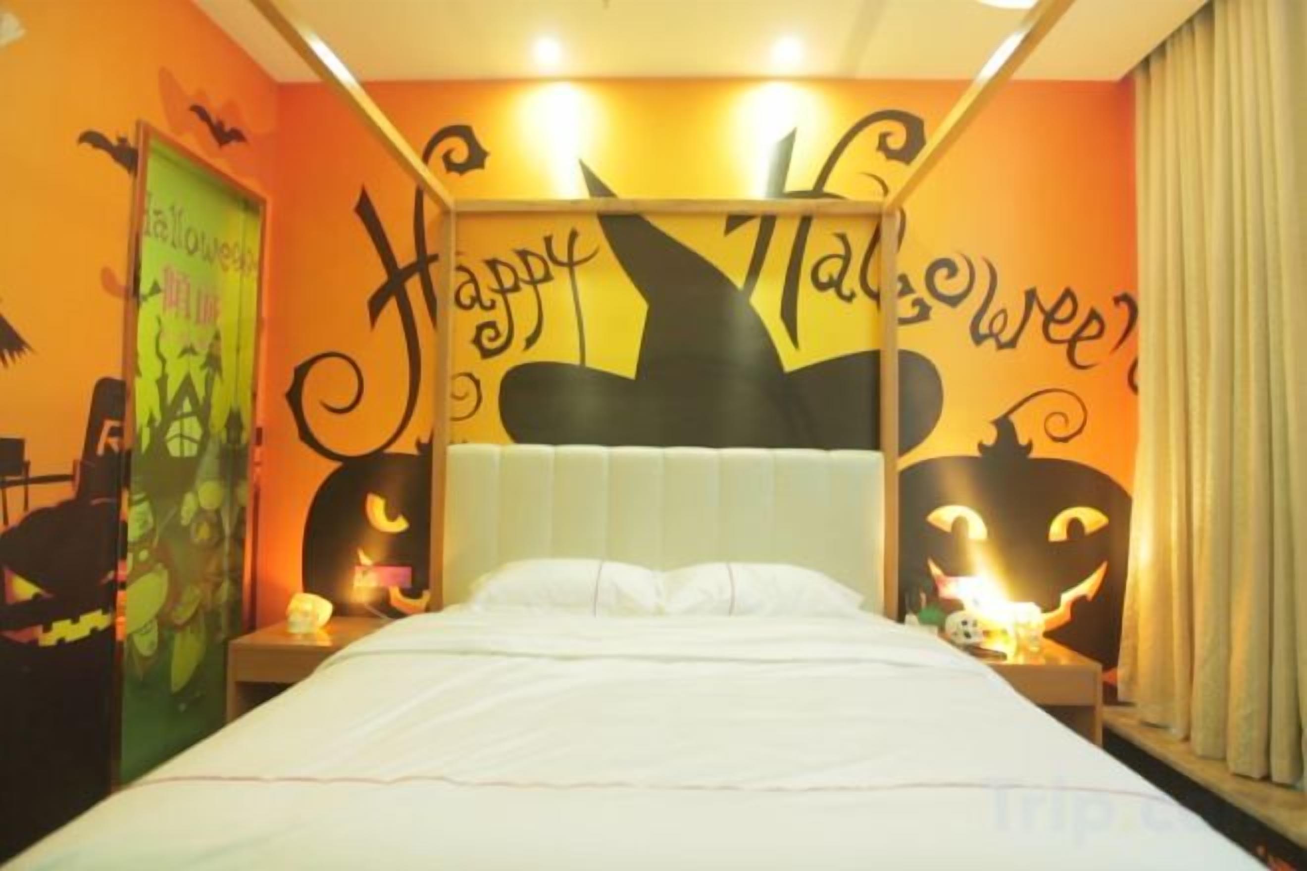 Una habitación con una cama, una mesita de noche y una pared decorada con motivos de Halloween.