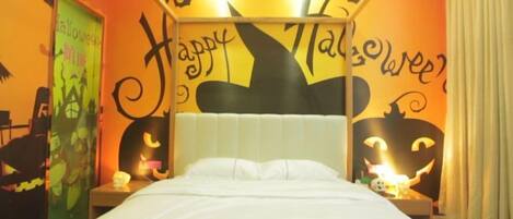 Una habitación con una cama, una mesita de noche y una pared decorada con motivos de Halloween.