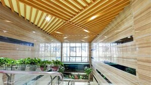 A modern interior with a wooden ceiling, glass walls, and a central staircase. - Yueyang Qingcheng Theme Hotel (Yueyang County)