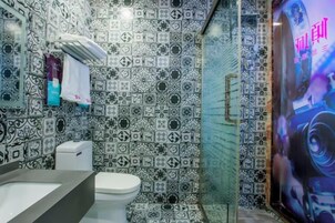 Un baño con azulejos estampados, un lavabo, un inodoro y una zona de ducha.