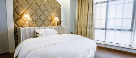 Un dormitorio moderno con un cabecero capitonado, cama redonda, lámparas de noche y un ventanal amplio.