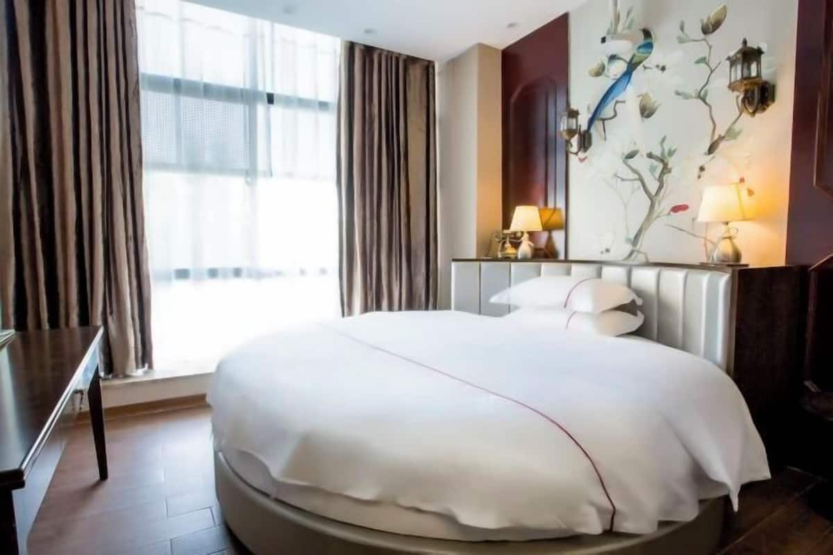 Une chambre d’hôtel avec un grand lit, un bureau et une fenêtre avec des rideaux.