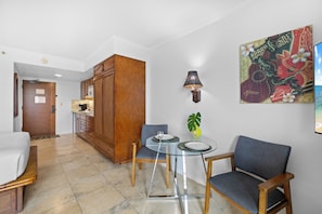 Une chambre d’hôtel comprenant un coin repas, un lit, une cuisine et une grande affiche au mur.