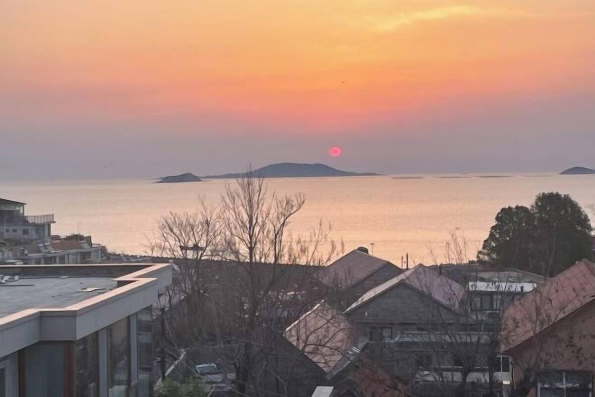 Küstenansicht mit Sonnenuntergang, Gebäuden und ruhiger See.