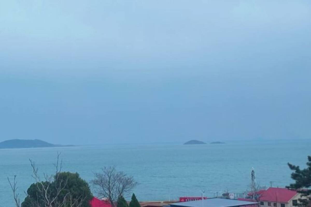 Küstensicht mit Gebäuden, blauem Himmel und ruhiger See.