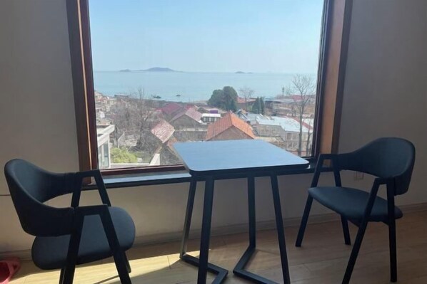 Une pièce avec une grande fenêtre, deux chaises et une petite table.