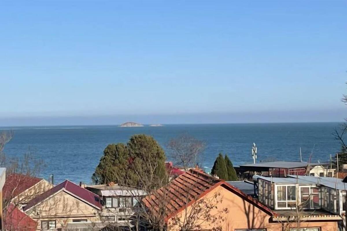 Ein Küstenwohngebiet mit Häusern, einem klaren Himmel und dem Meer im Hintergrund.