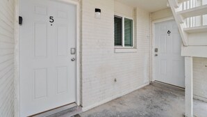 A white building with two doors, numbered 5 and 6, and a small window with shutters. - NEW! Modern 3-Bedroom Retreat Fully Updated! (El Paso)