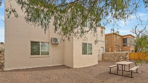 A building with a patio area featuring a table and benches, surrounded by a gravel ground and stone walls. - NEW! Modern 3-Bedroom Retreat Fully Updated! (El Paso)