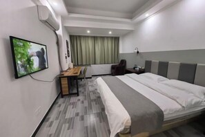 A hotel room with a bed, desk, chair, and a TV mounted on the wall. - Guanglian Hotel (Shenzhen Bao'an Airport Huangtian Subway Station) (Shenzhen)