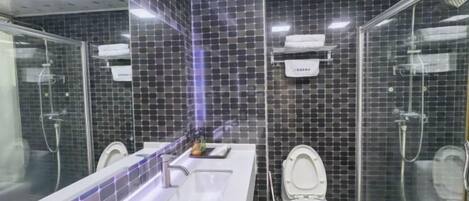 A modern bathroom with a large sink, two toilets, and a glass-enclosed shower area.