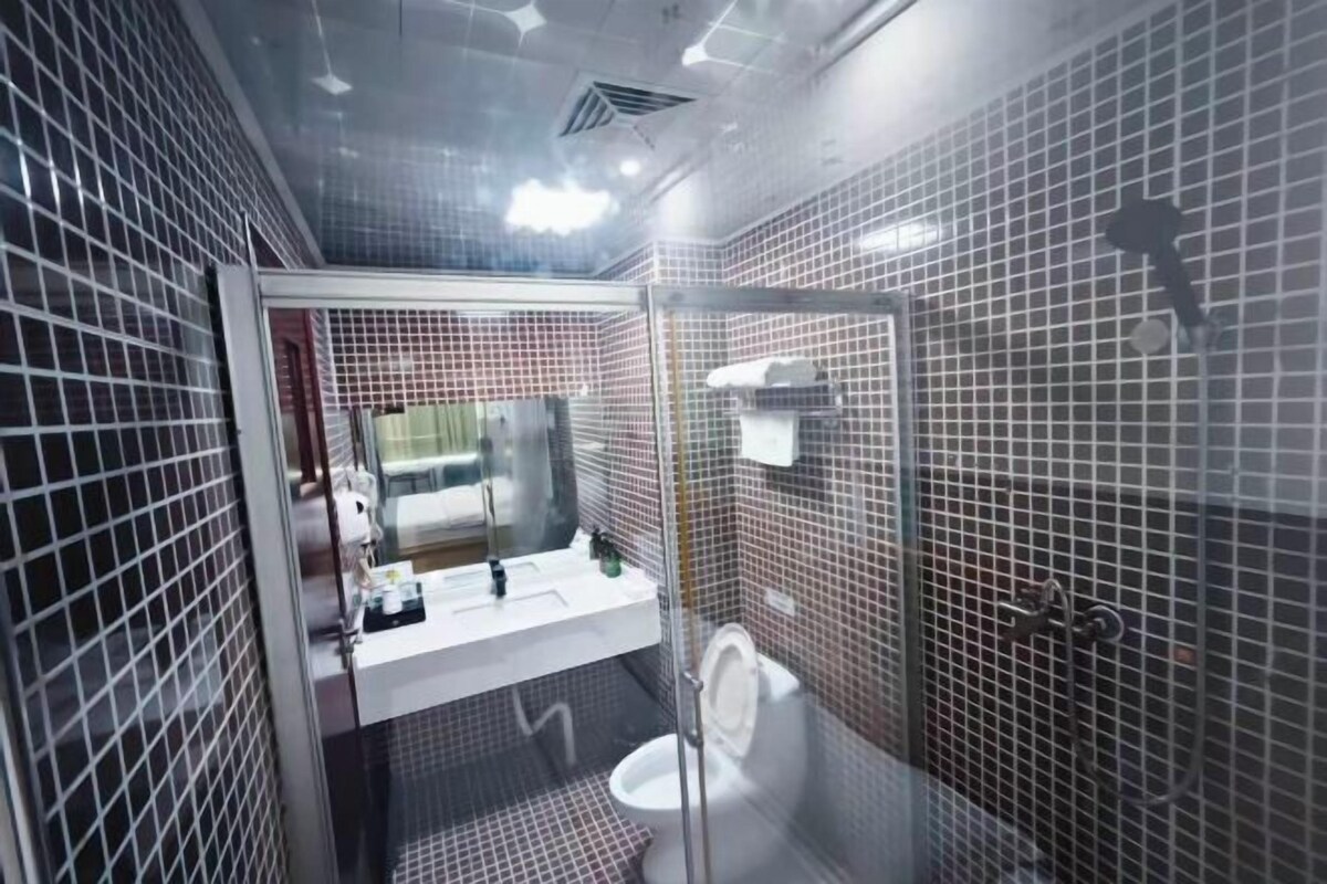 A modern bathroom with a glass-enclosed shower, a white sink with a mirror, and a toilet.