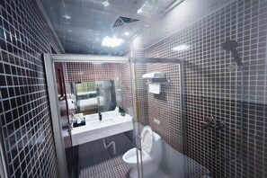 A modern bathroom with a glass-enclosed shower, a white sink with a mirror, and a toilet. - Guanglian Hotel (Shenzhen Bao'an Airport Huangtian Subway Station) (Shenzhen)