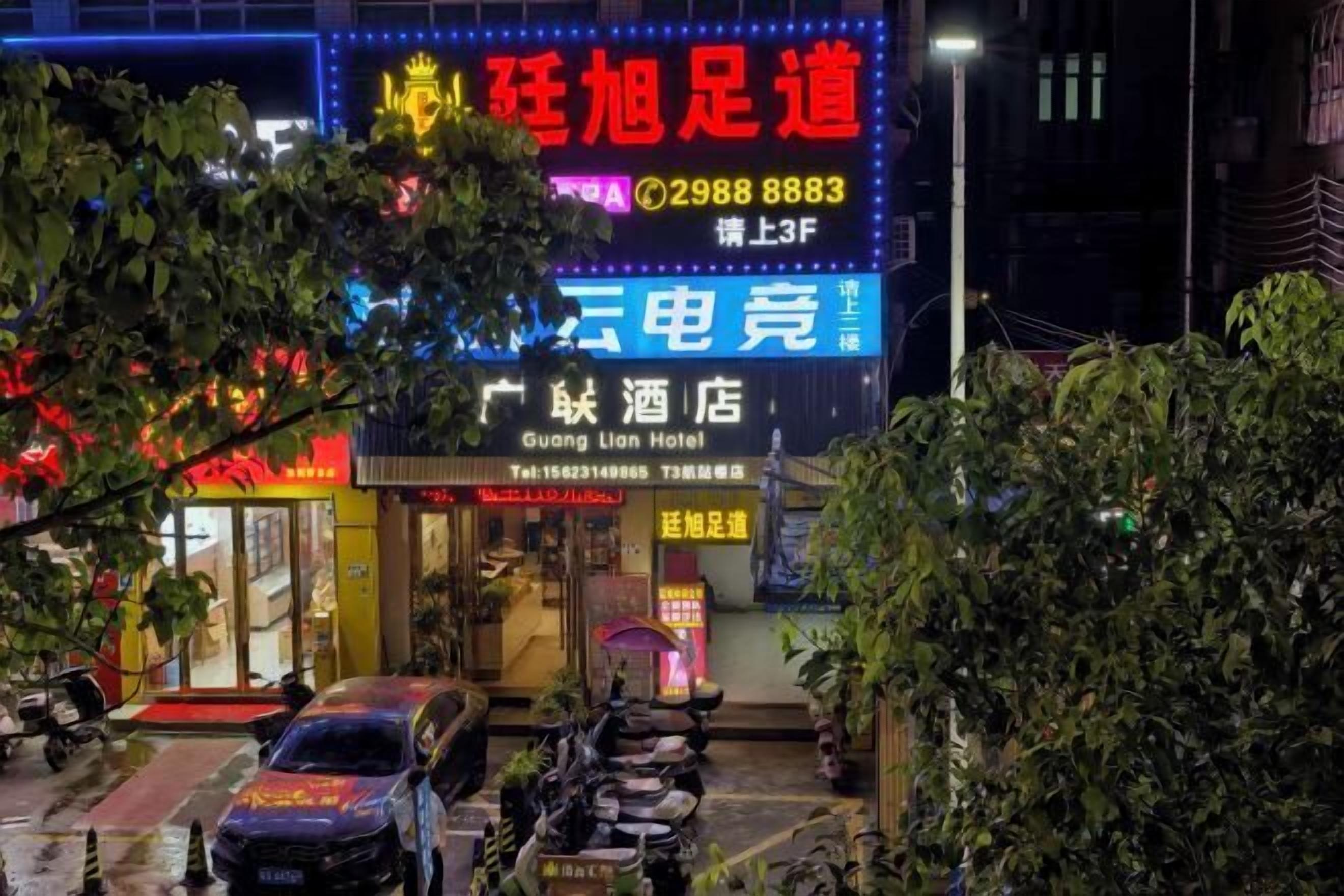 A hotel with a neon sign, a visible entrance, and a parked car.