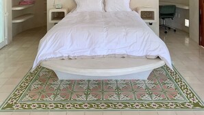 Une chambre avec un grand lit, un élément de décoration murale circulaire, un puits de lumière et un tapis à motifs.