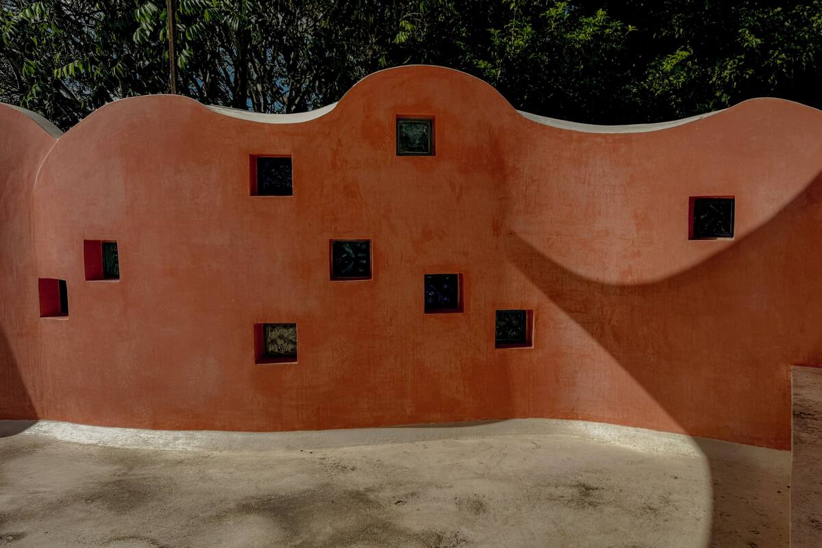 Pared curva con varias ventanas pequeñas y piso de concreto.