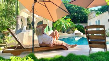 Alberca al aire libre, sombrillas en la alberca y camastros
