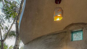 A kitchen with a sink, a faucet, a shelf with items, and a hanging light fixture. - CalleOuvert (Mérida)