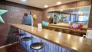 Une cuisine avec un mur en briques, un comptoir de bar avec des tabourets et un grand miroir.