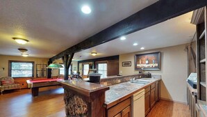 A spacious living area with a pool table, wooden flooring, and a kitchen with a large island. - Bugle Point - Unit I1 (Ruidoso)