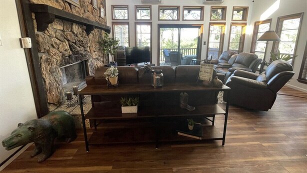 A living room with a stone wall, a fireplace, a sofa, a coffee table, and a television.