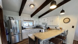 A modern kitchen with a central island, stainless steel appliances, and a rustic wooden floor.