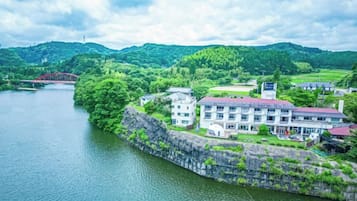 A riverside hotel with a stone wall, multiple buildings, and a view of the river.
