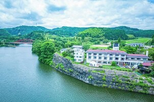 Un hotel a orillas del río con muro de piedra, varios edificios y vista al río.