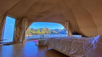 A bedroom with a large bed, a view of a lake, and a mountain in the background.