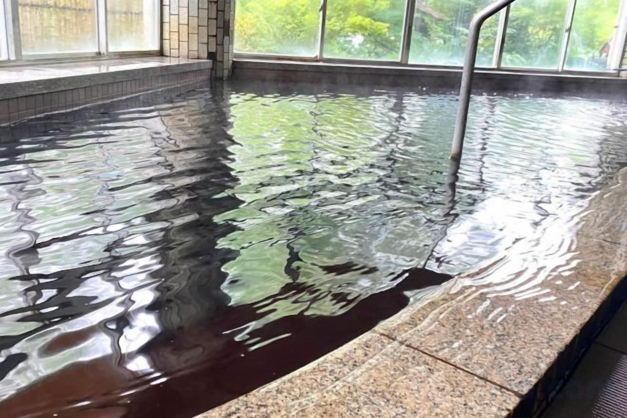 A swimming pool with a clear water surface and a metal ladder.