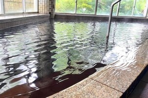 Una piscina con superficie de agua cristalina y una escalera metálica.