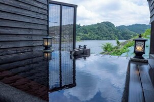 Una terraza de madera con vistas a un lago y colinas.