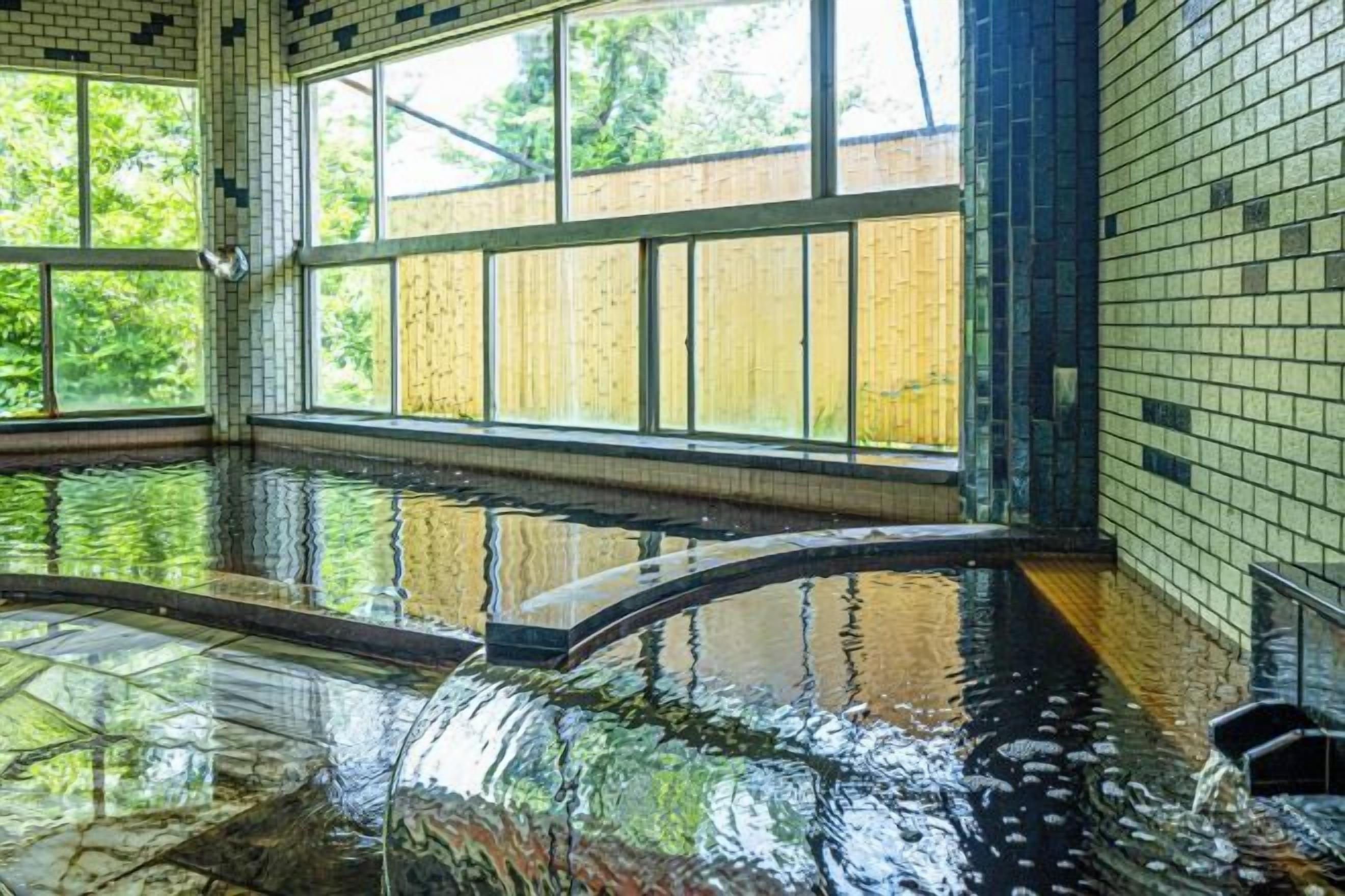 An indoor swimming pool with clear glass walls and a tiled floor.