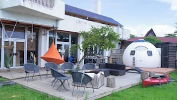 A modern house with a deck, outdoor seating, and a unique spherical structure.