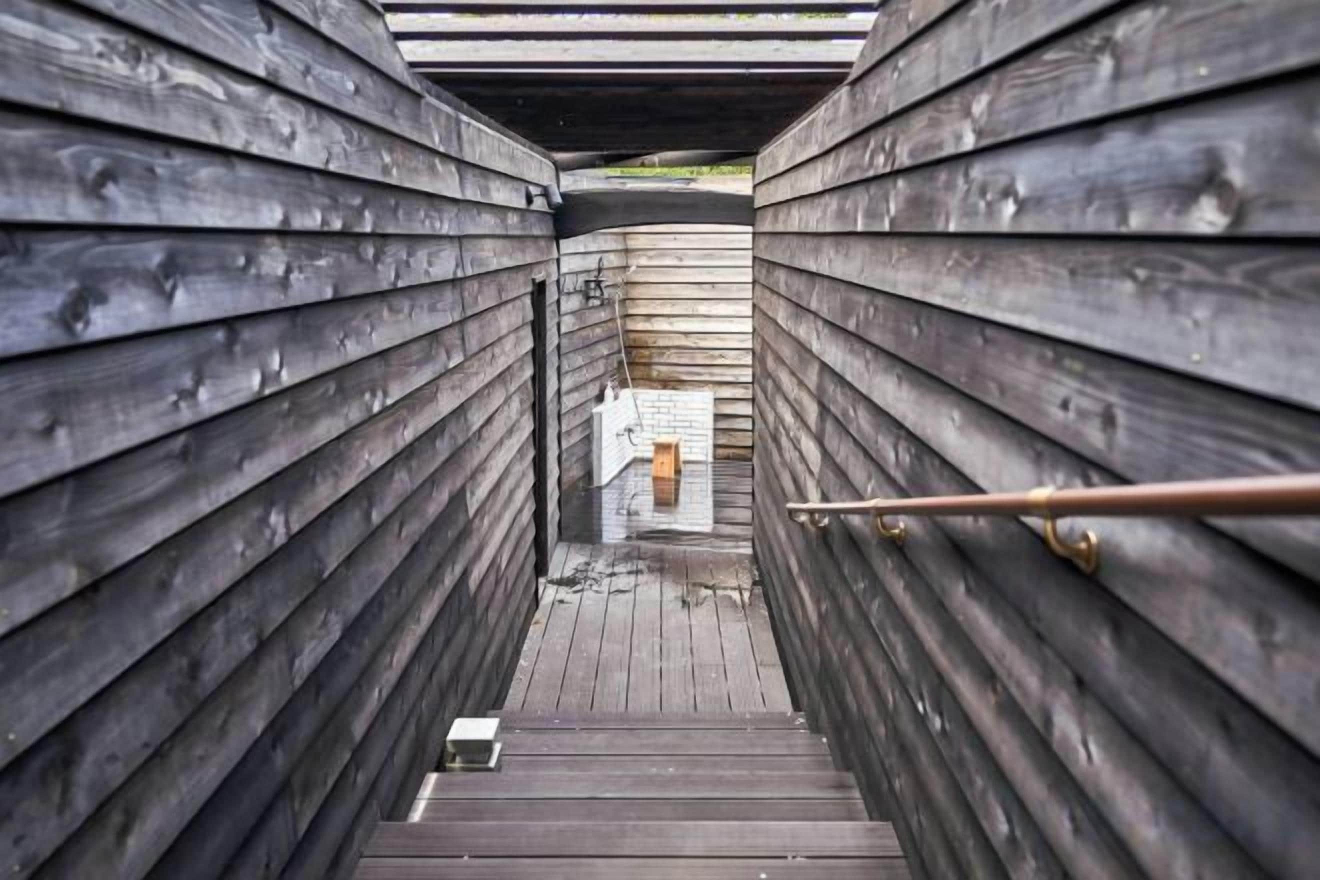 A wooden staircase leading to a covered area with a metal railing.
