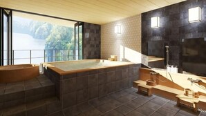 Ein modernes Badezimmer mit einer großen Badewanne, einer Holzbalkendecke und Seeblick.