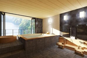 Un baño moderno con una bañera grande, techo de madera y vistas a un lago.