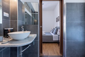 A modern bathroom with a large white vessel sink, a mirror, and a shower area. - Hesa House (Cagliari)