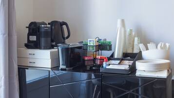 Área de desayuno en una habitación de hotel, con cafetera, tetera y diversas opciones para el desayuno.