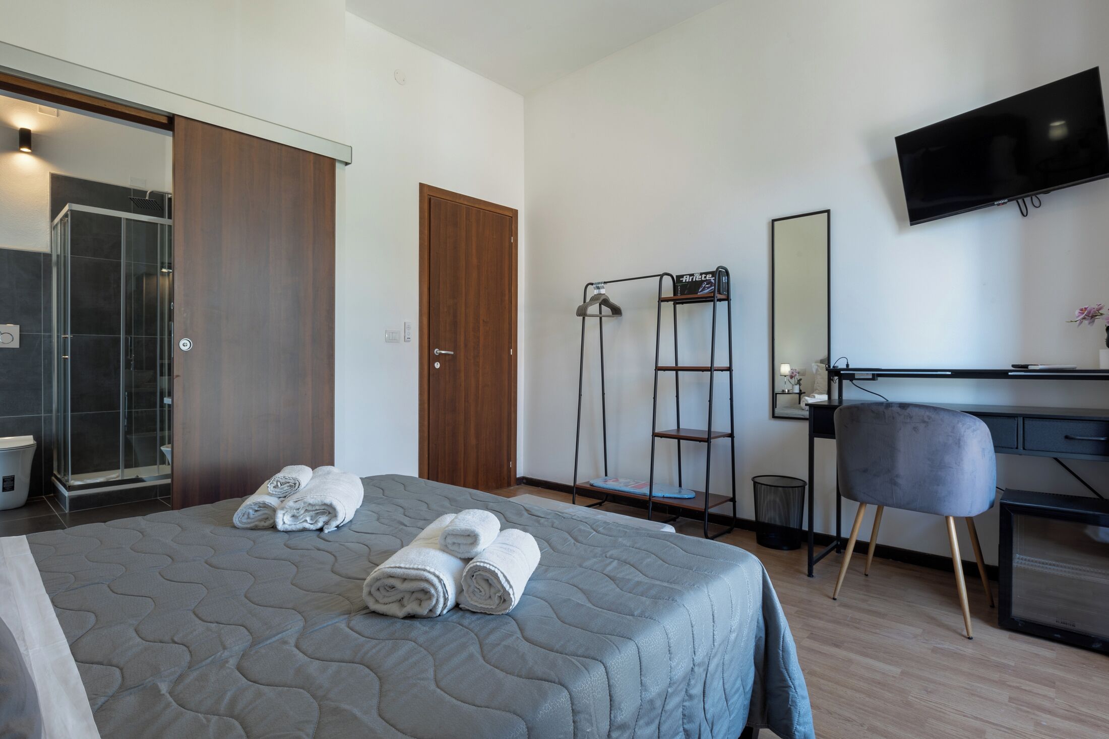 Een hotelkamer met een bed, een bureau, een stoel, een televisie en een douche.