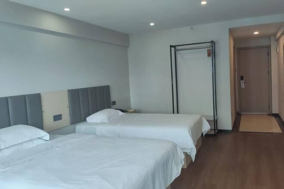 Een hotelkamer met twee bedden, een hoofdbord, een kledingkast en een deur.