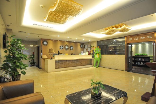 A hotel reception area with a reception desk, a green plush toy, and a plant.