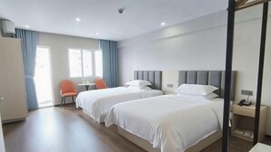 Une chambre d’hôtel avec deux lits, un bureau, une chaise et une fenêtre.