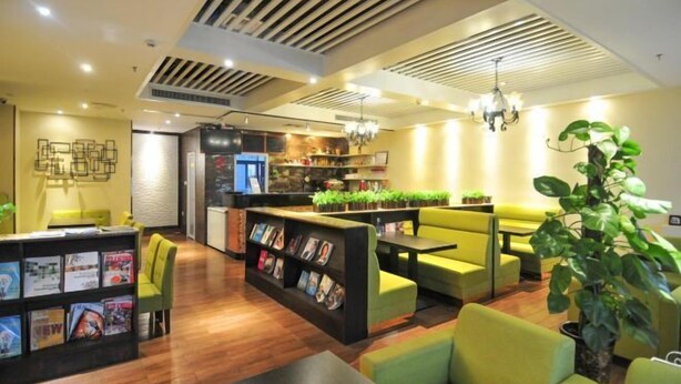 Un hall d’hôtel moderne avec un comptoir d’accueil, un espace salon et une bibliothèque.