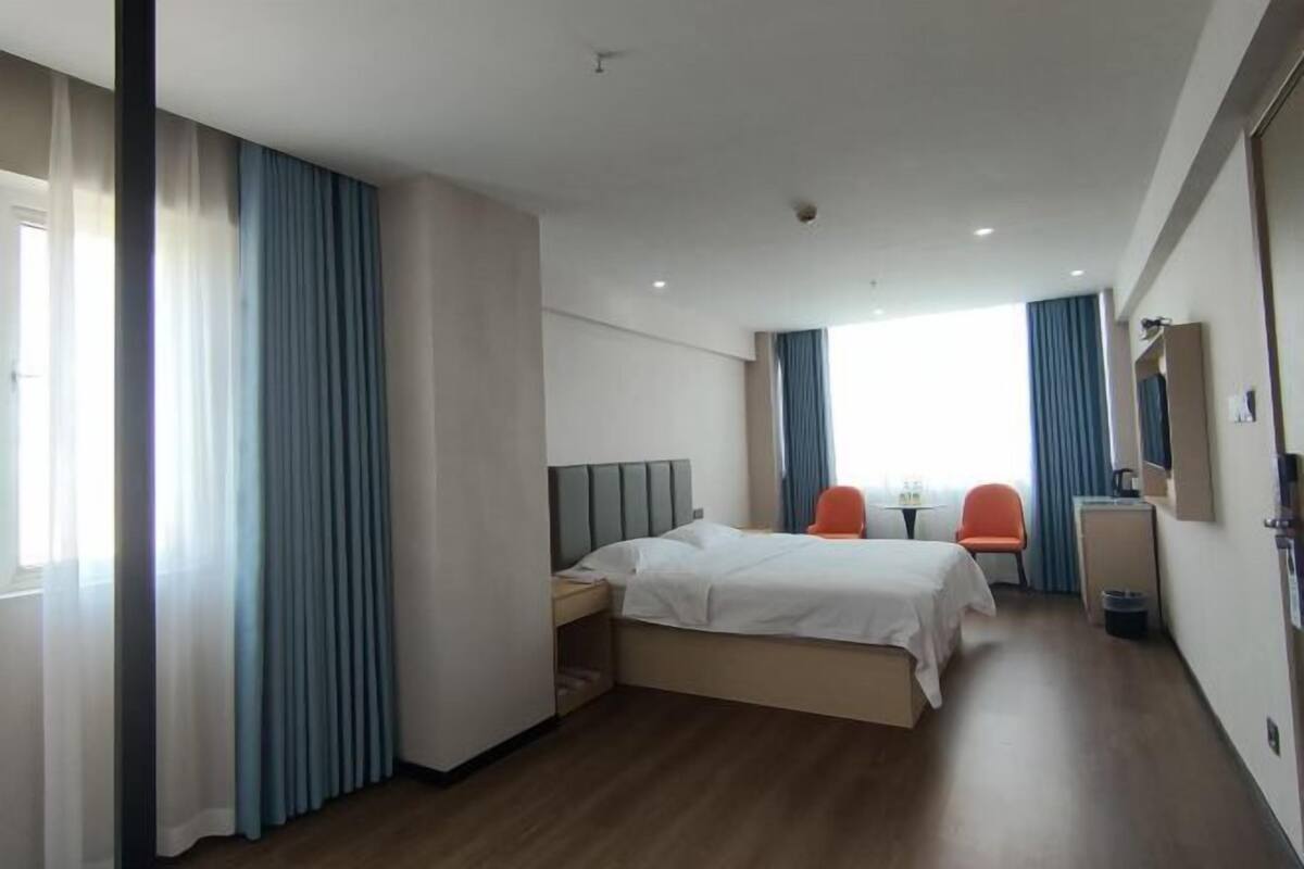 Een hotelkamer met een bed, twee stoelen, een bureau en een spiegel.