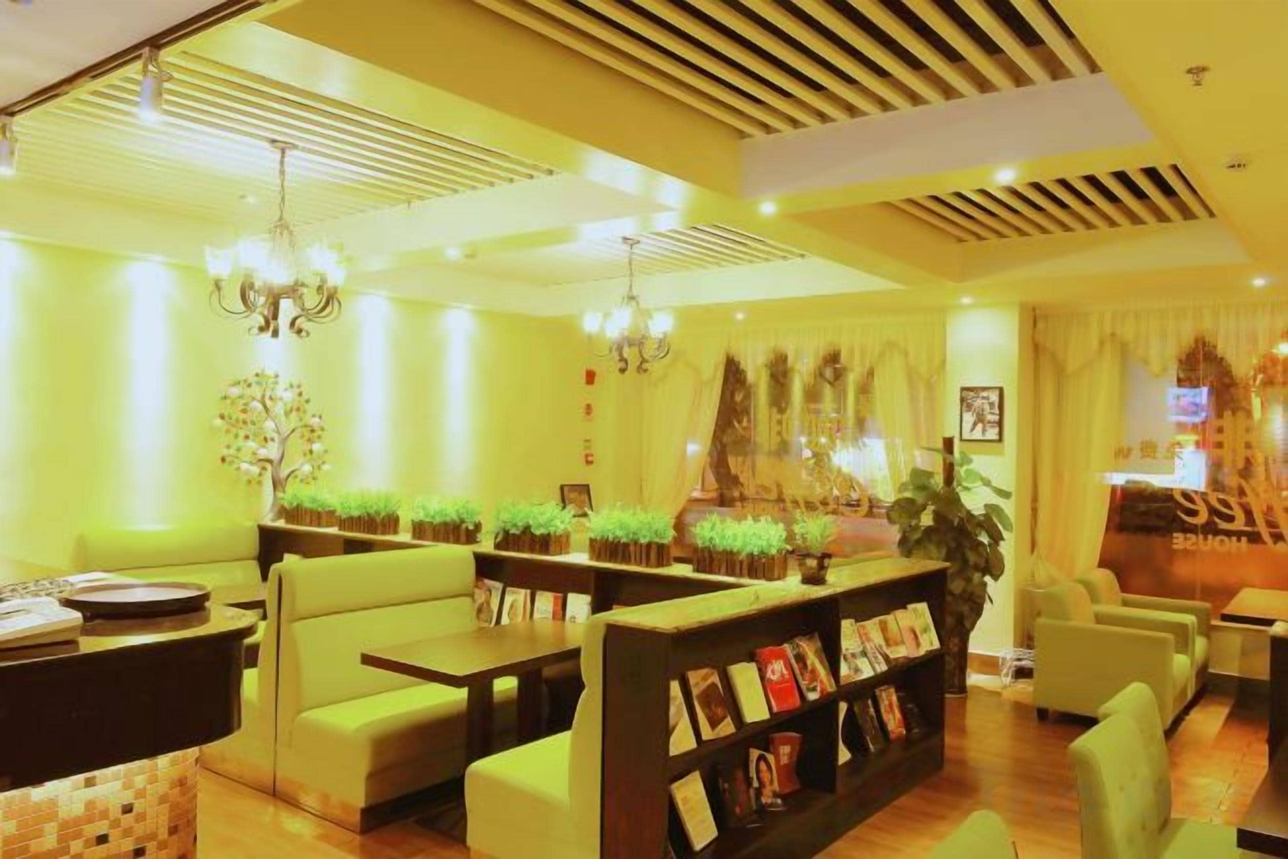 A hotel lobby with seating areas, a reception desk, and decorative plants.
