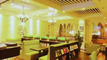 A hotel lobby with seating areas, a reception desk, and decorative plants.