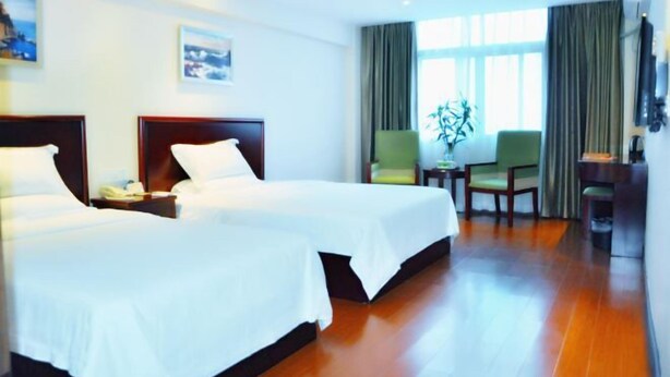 A hotel room with two beds, a small table with a plant, a chair, and a TV mounted on the wall. - GreenTree Inn Hainan Haikou Qilou Old Street Haifu Road Express Hotel (Haikou)
